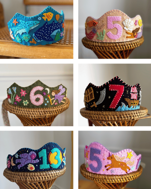 Collection of colorful children's birthday crowns with numbers and patterns on a wooden stand.