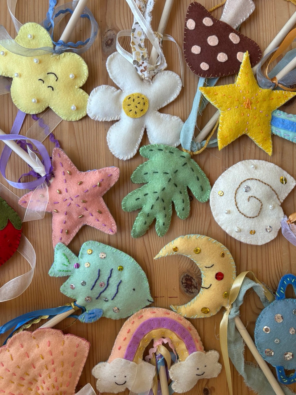 Collection of colorful felt wand decorations on a wooden surface