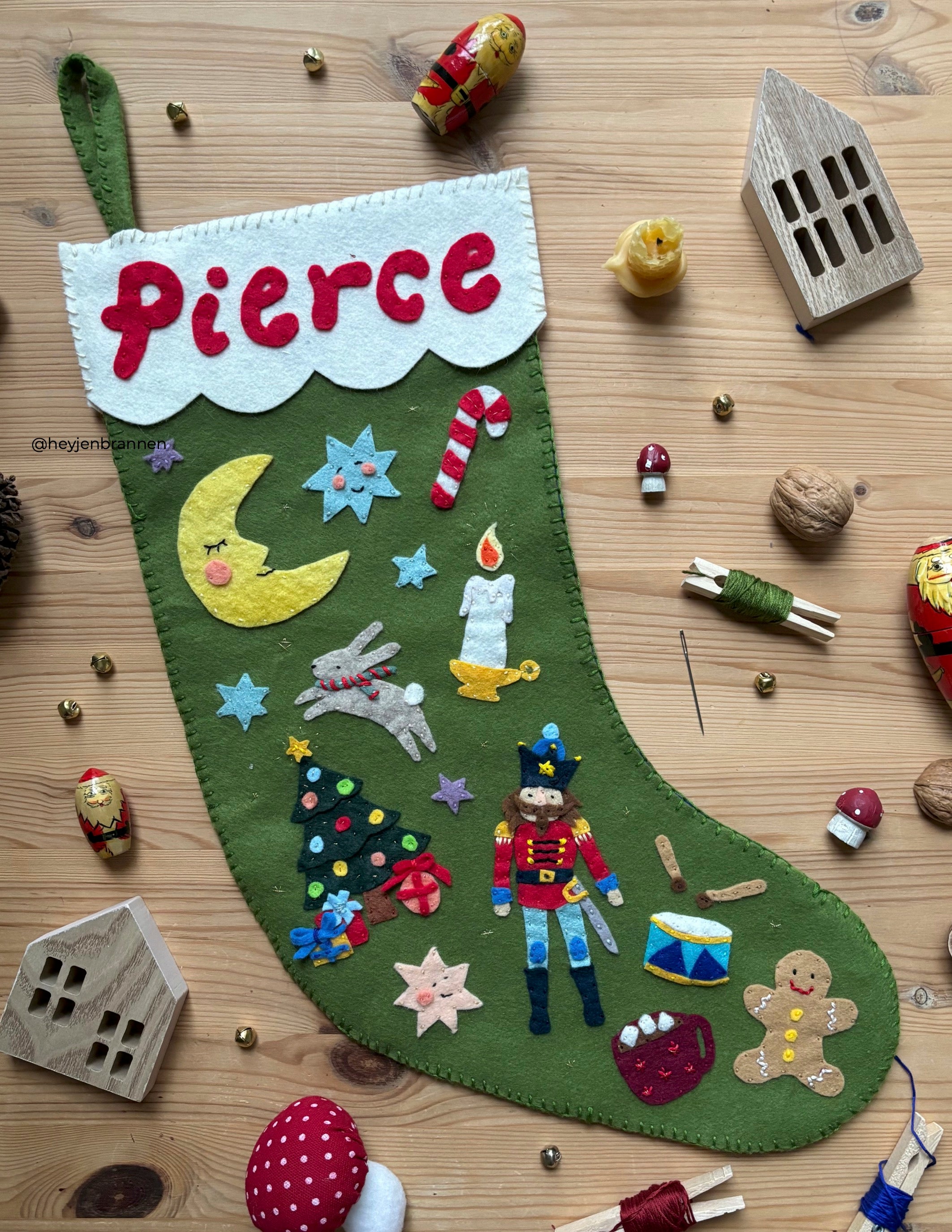 Personalized felt Christmas stocking with festive designs on a wooden surface.