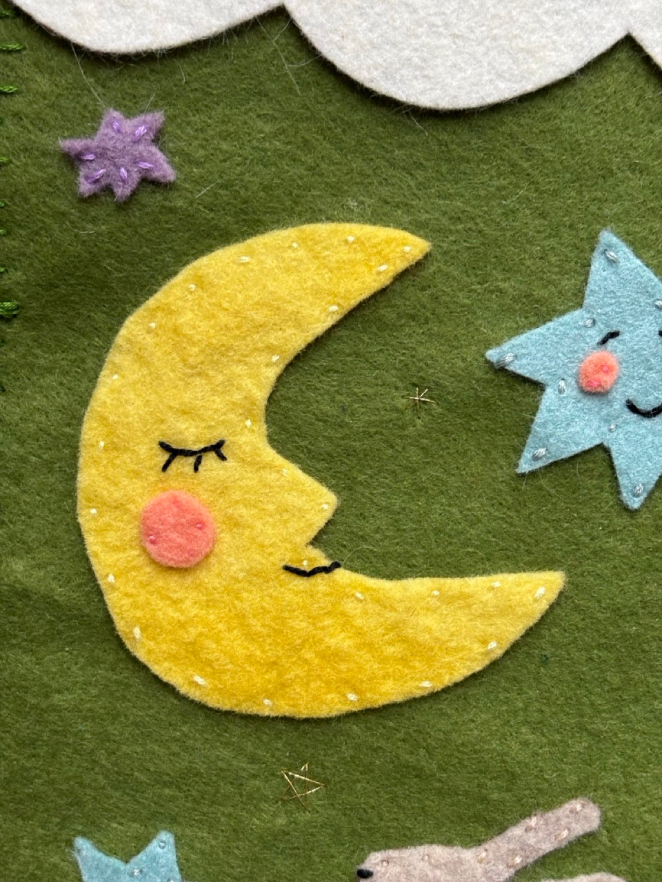 Felt moon and star decoration on a green background