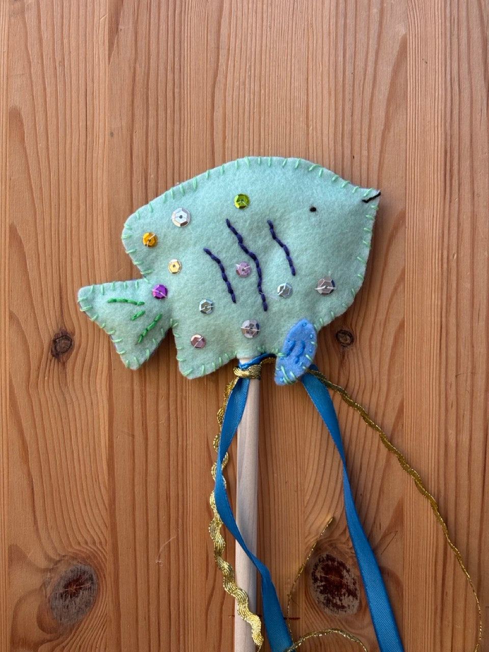 Decorative fish wand with ribbons on a wooden surface