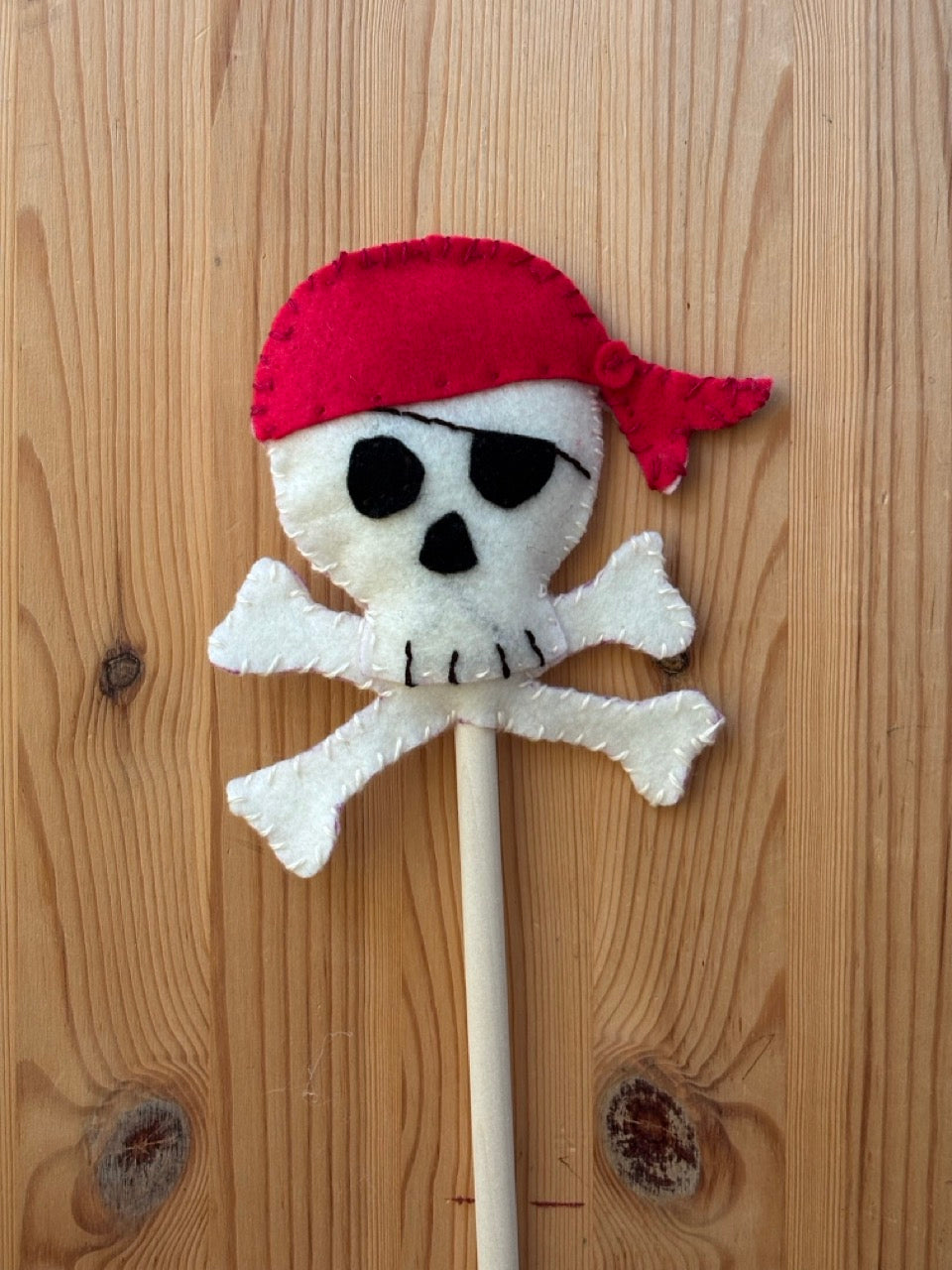 Pirate-themed wand with skull and crossbones design on a wooden surface