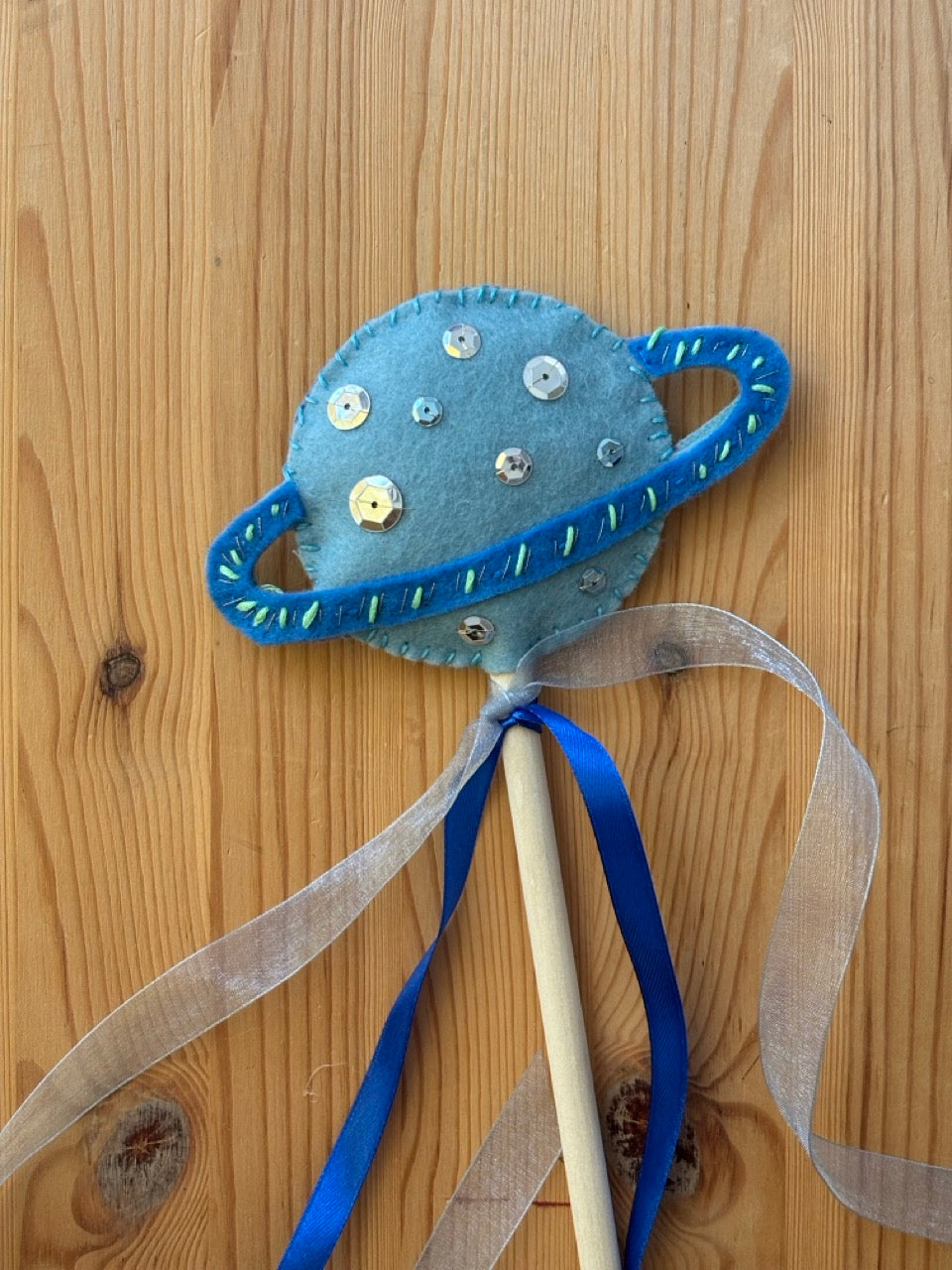 Decorative planet wand with ribbons on a wooden surface